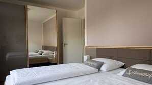 Una habitación de hotel con cama, mesita de noche, espejo y armario.