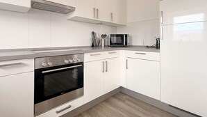 Una cocina moderna con armarios blancos, horno de acero inoxidable, microondas y refrigerador.