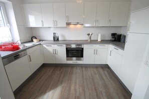 Eine moderne Küche mit weißen Schränken, einem Edelstahlbackofen und Holzboden.