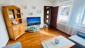 Una sala de estar con un aparador de madera, un televisor, un sofá y una mesa.