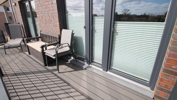 Un balcon avec un plancher en bois, un banc et une chaise.