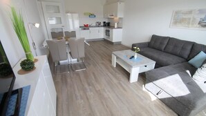 Un salon moderne avec un canapé gris, une table basse et un coin repas comprenant une table et des chaises.