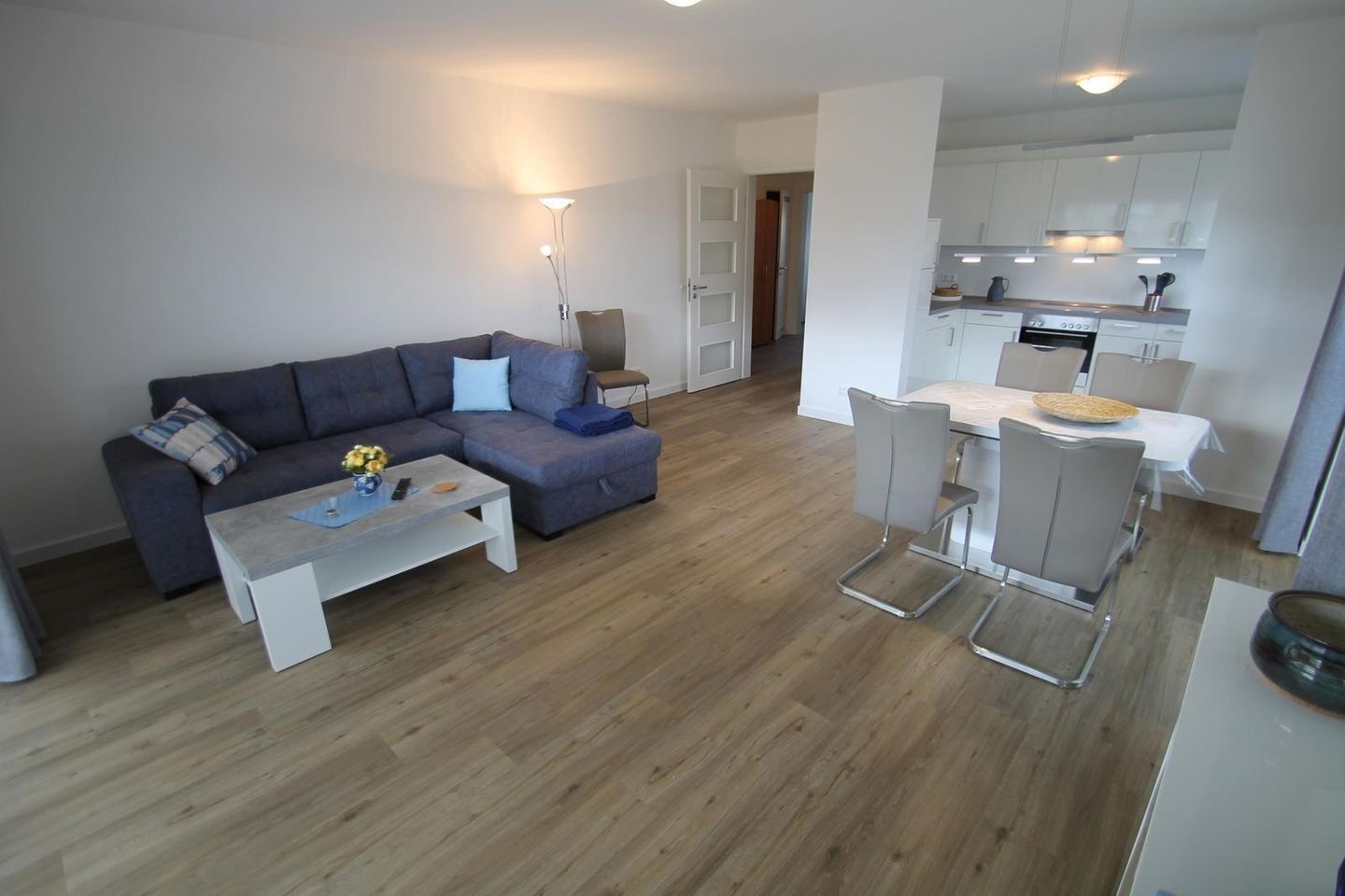 A modern living room with a sofa, coffee table, and dining area with chairs.