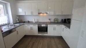 A modern kitchen with white cabinets, a stainless steel oven, and a built-in dishwasher.