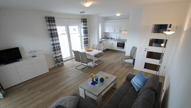 A modern apartment with a living room, dining area, and kitchen.