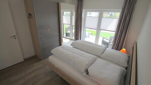 Un dormitorio con cama, armario y ventana con cortinas.