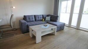 Una sala de estar moderna con un sofá seccional gris, una mesa de centro blanca y una lámpara de pie.