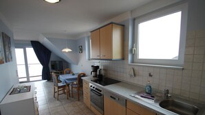 A compact kitchen with a dining area, a window, and a view of the outdoors.