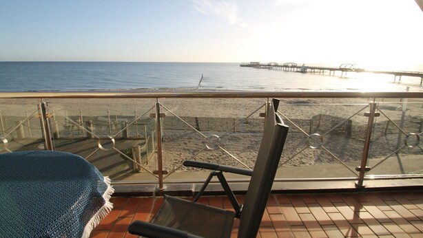 A balcony with a view of the beach and a pier.