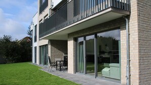 A modern two-story house with a balcony, sliding glass doors, and a well-maintained lawn. - 2602 - Strandwiese 18 - Apartment 2602 in the Strandwiese (Dahme)