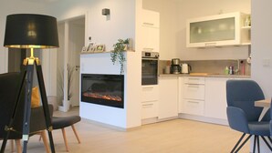 A modern kitchen with white cabinets, a built-in oven, a microwave, and a large window above the sink. - 2602 - Strandwiese 18 - Apartment 2602 in the Strandwiese (Dahme)