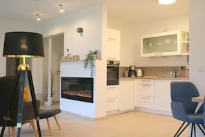 Una cocina moderna con armarios blancos, horno integrado, microondas y un amplio ventanal sobre el fregadero.