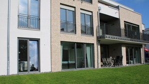 A modern building with multiple balconies, large windows, and a grassy lawn. - 2602 - Strandwiese 18 - Apartment 2602 in the Strandwiese (Dahme)