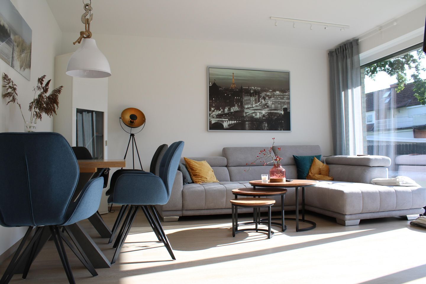 Una sala de estar moderna con un sofá, sillas, una mesa de centro y una lámpara de pie.