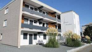Un edificio de varios pisos con balcones, un banco y un cartel que dice 'Oinen Residenz'.
