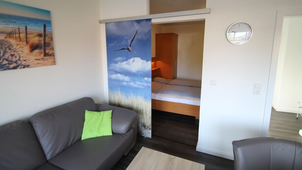 Un espacio habitable compacto con un sofá, una cama y un reloj en la pared.