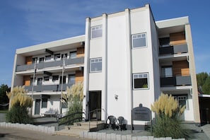 A multi-story residential building with balconies, a sign indicating it is a Dürener Residenz, and outdoor seating. - 1515 - Dünenresidenz WG 5 - Dünenresidenz apartment 5 (Dahme)