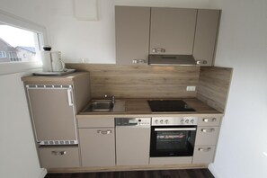 A compact kitchen with a dishwasher, oven, and a coffee maker on the counter. - 1515 - Dünenresidenz WG 5 - Dünenresidenz apartment 5 (Dahme)