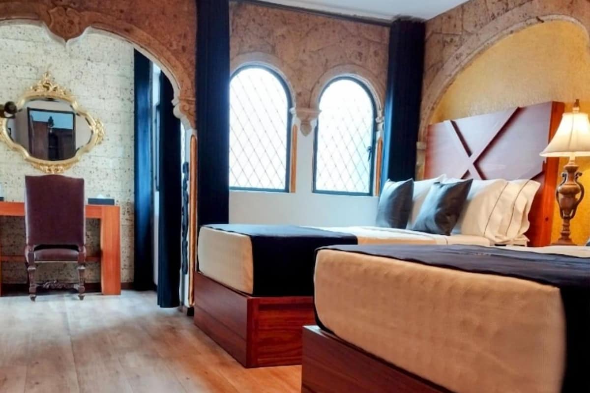 Ein Schlafzimmer mit einem großen Bett, einem Schreibtisch und einer Chandelier.
