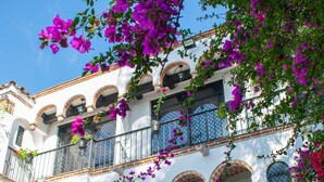Un edificio con múltiples balcones, ventanas en arco y fachada blanca.