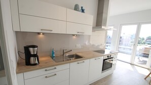 Une cuisine moderne avec des meubles blancs, un plan de travail en bois, une machine à café, un évier et un four.
