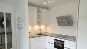 Una cucina moderna con mobili bianchi, forno integrato e microonde a parete.