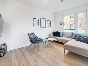 A modern living room with a sofa, a chair, a small table, and a coffee table. There are three framed pictures on the wall.