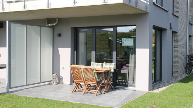 Un edificio moderno con un patio cubierto que incluye una mesa y sillas.