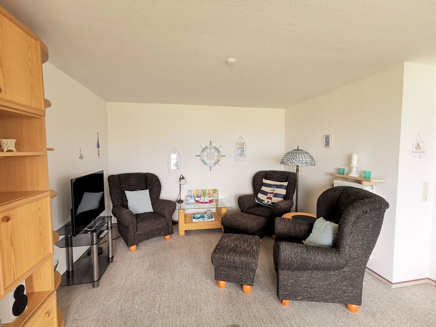 A living room with a TV, two armchairs, a coffee table, and a bookshelf.