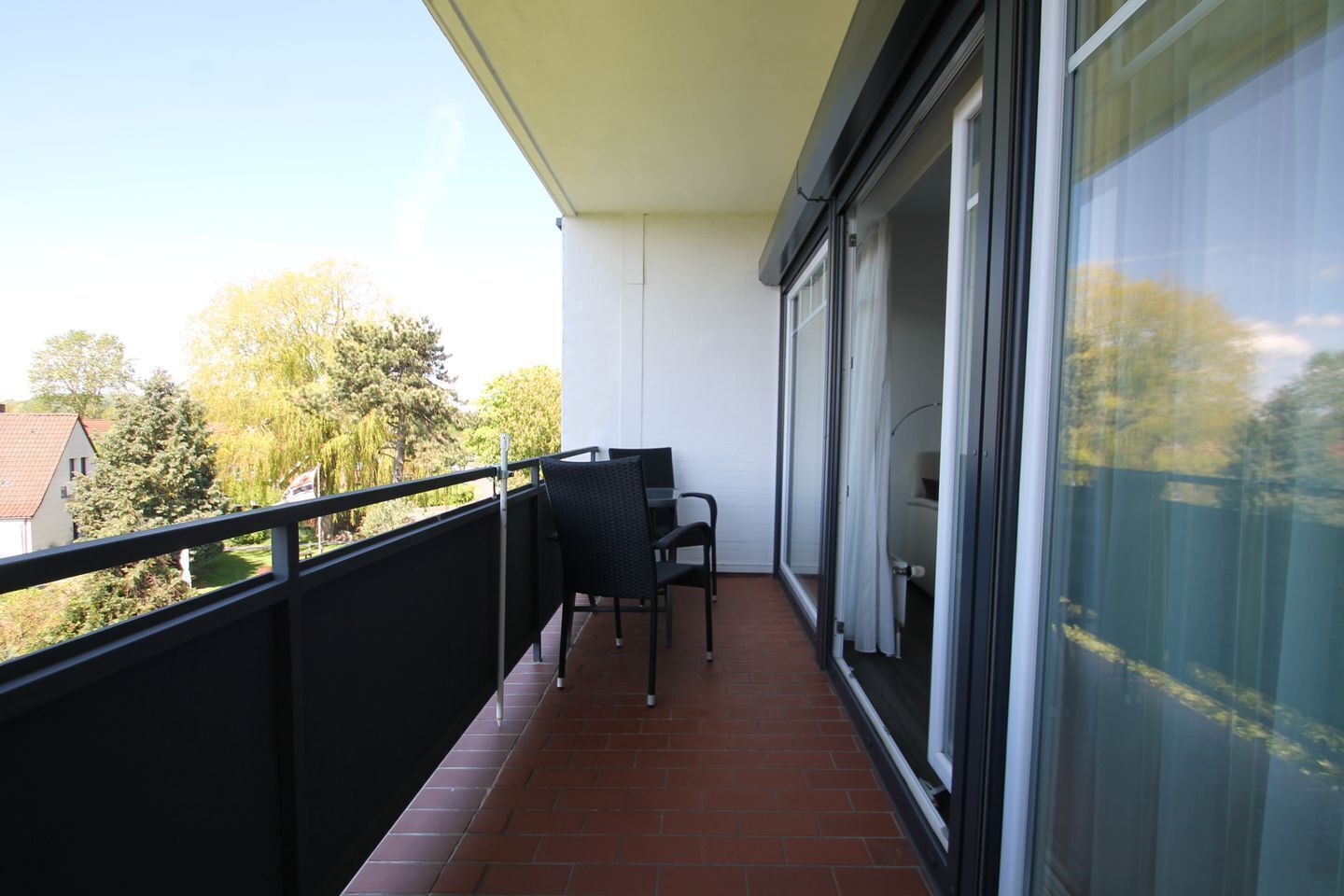 A balcony with a black railing, a small table, and two chairs.
