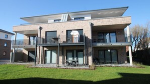 A modern two-story residential building with balconies, large windows, and a flat roof.