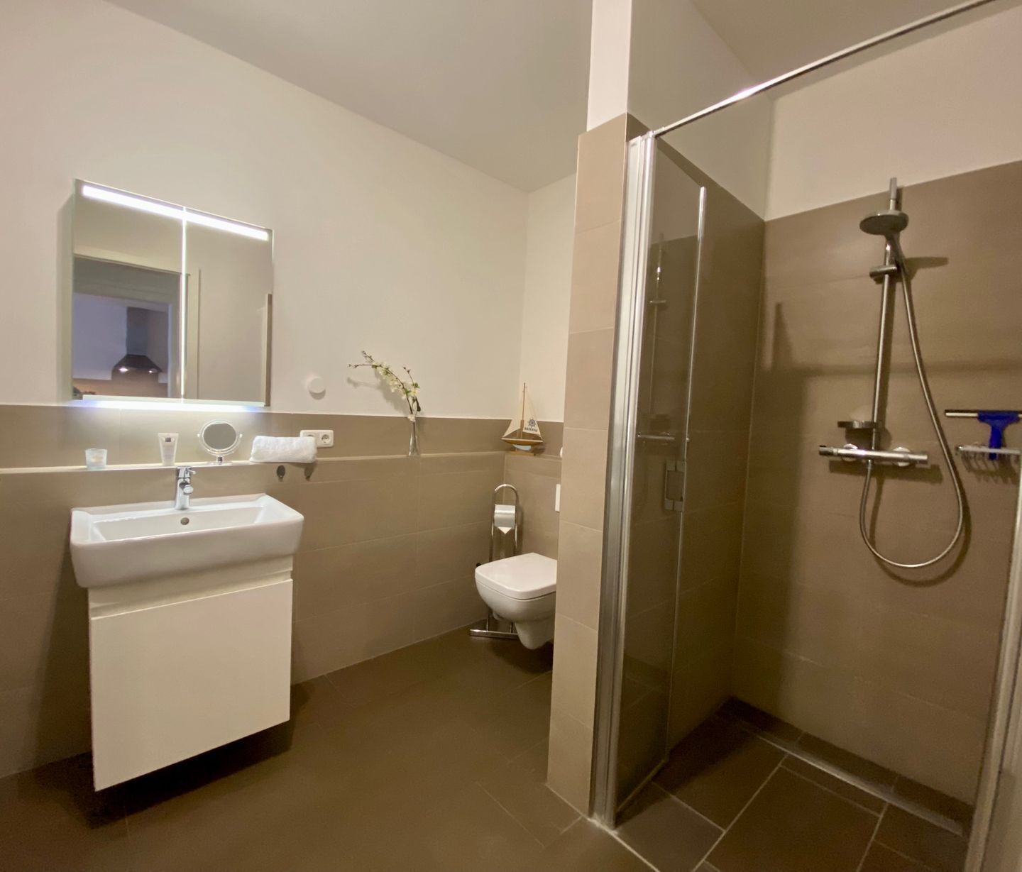 Une salle de bain moderne avec un lavabo, des toilettes et une douche à parois de verre.