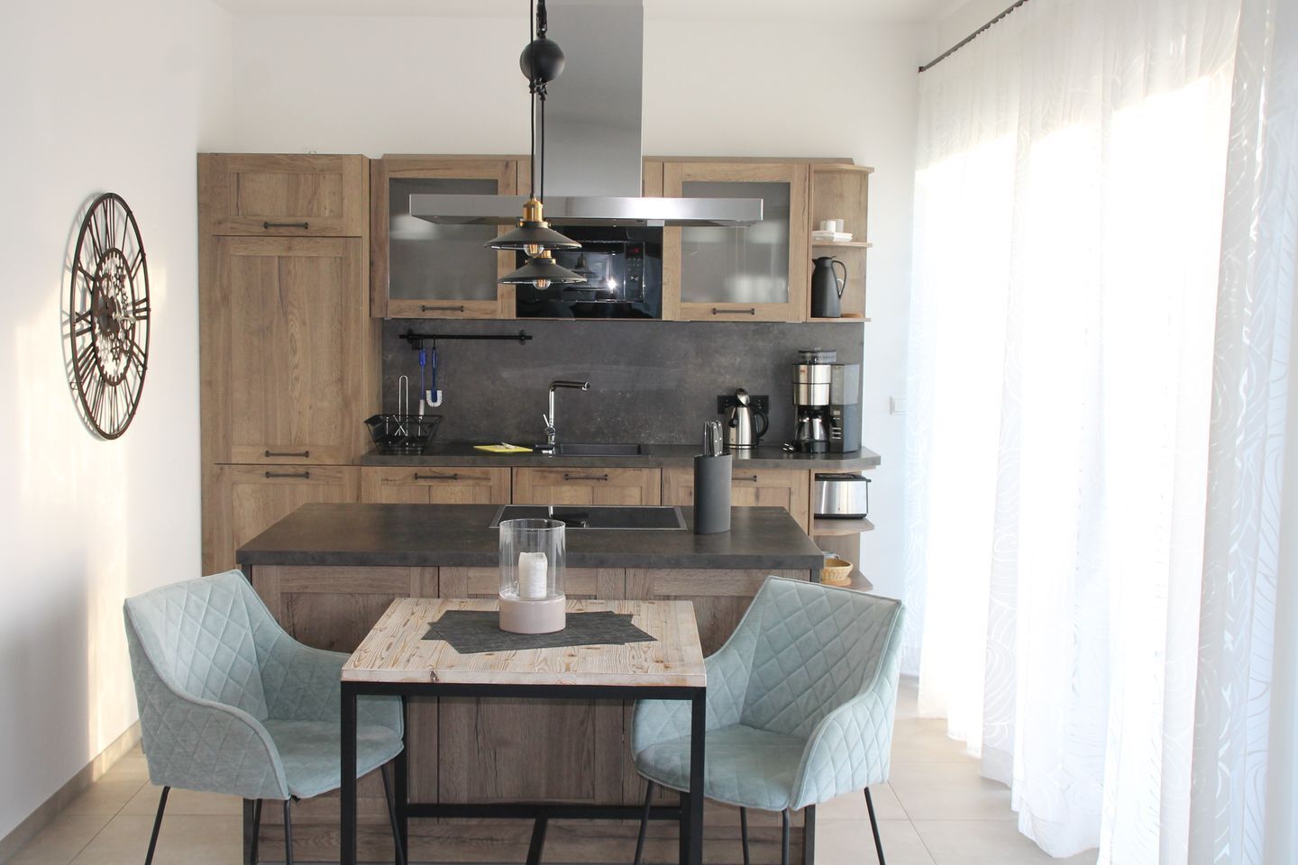 Een moderne keuken met houten kastjes, een centraal eiland en een eethoek met twee stoelen.