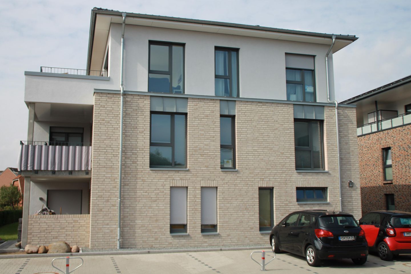 Un edificio moderno de dos pisos con techo plano, ventanas grandes y fachada de ladrillo.