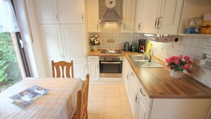 Una cocina compacta con armarios blancos, una encimera de madera, un fregadero y una estufa.