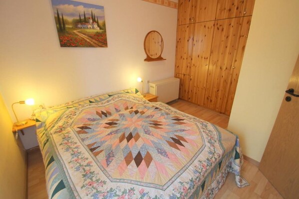 Un dormitorio con una cama grande, paredes de madera, un cuadro en la pared y una puerta de madera.
