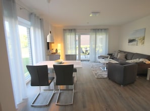 A modern living room with a dining area, large windows, and a view of the outdoors.