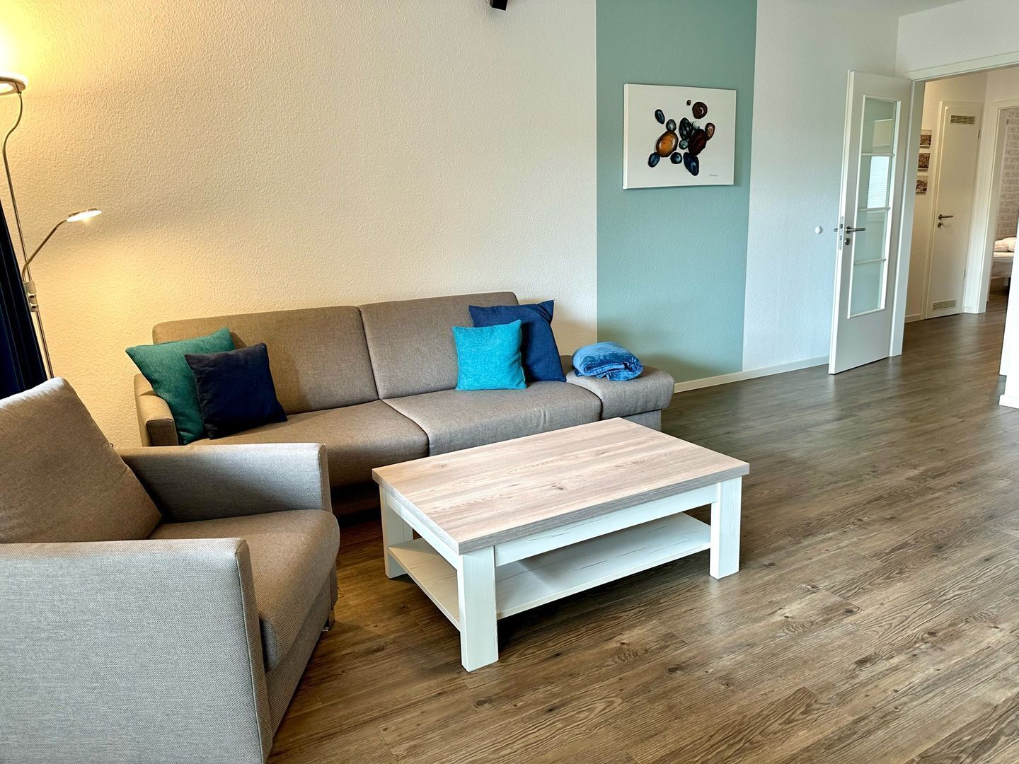 A modern living room with a sectional sofa, a coffee table, and hardwood flooring.