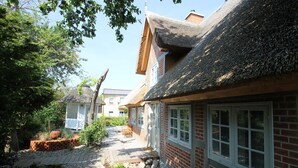A traditional cottage-style building with a thatched roof, brick walls, and a wooden deck.