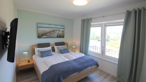 A bedroom with a bed, bedside tables, a painting, and a window with curtains.