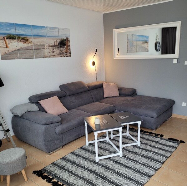 A modern living room with a grey sectional sofa, a small white coffee table, and a patterned rug.