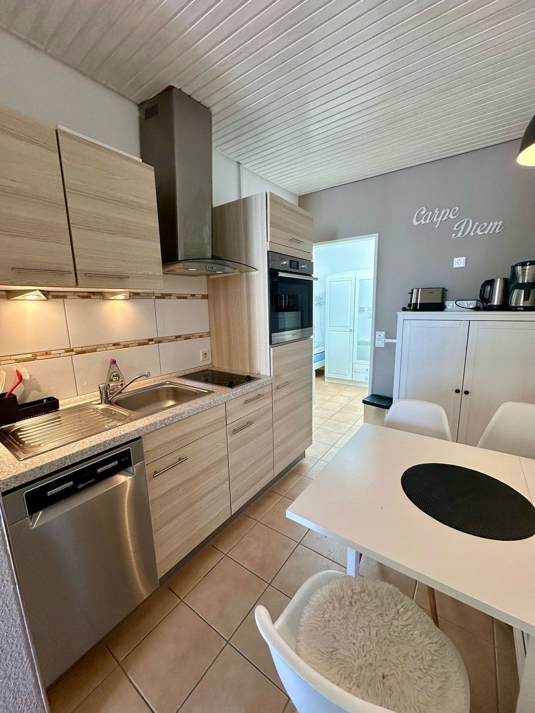 A modern kitchen with a dishwasher, sink, and a dining area with a table and chairs.