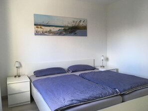 A bedroom with a bed, two bedside tables, and a wall-mounted lamp. - 1805 - Ostseestern - 1805 - Ostseestern in Dahme (Dahme)