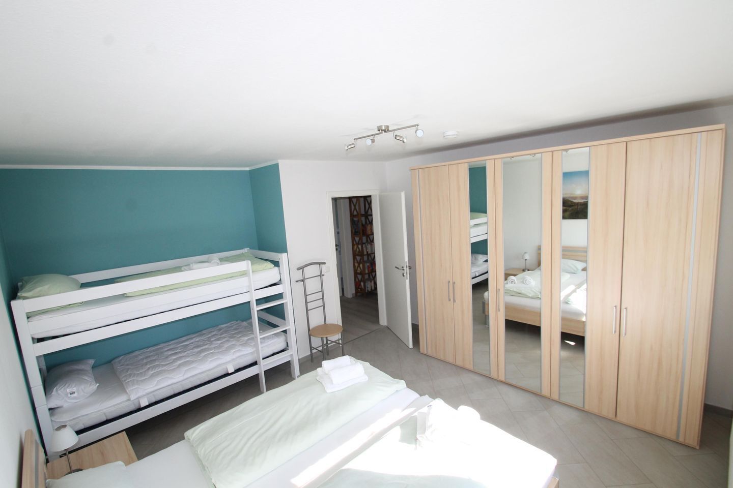 Une chambre avec des lits superposés, une armoire et une petite chaise.