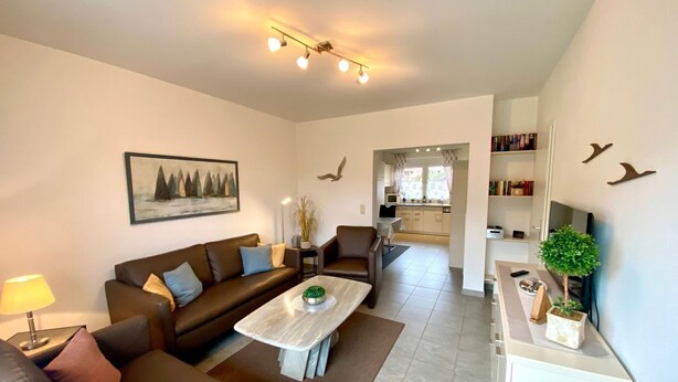 A modern living room with a brown leather sofa, a white coffee table, and a painting on the wall. - 2050 - House Heisterbusch (Kellenhusen (Ostsee))
