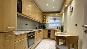 Une cuisine compacte avec des meubles en bois, un four encastré et un coin repas comprenant une table et des chaises.