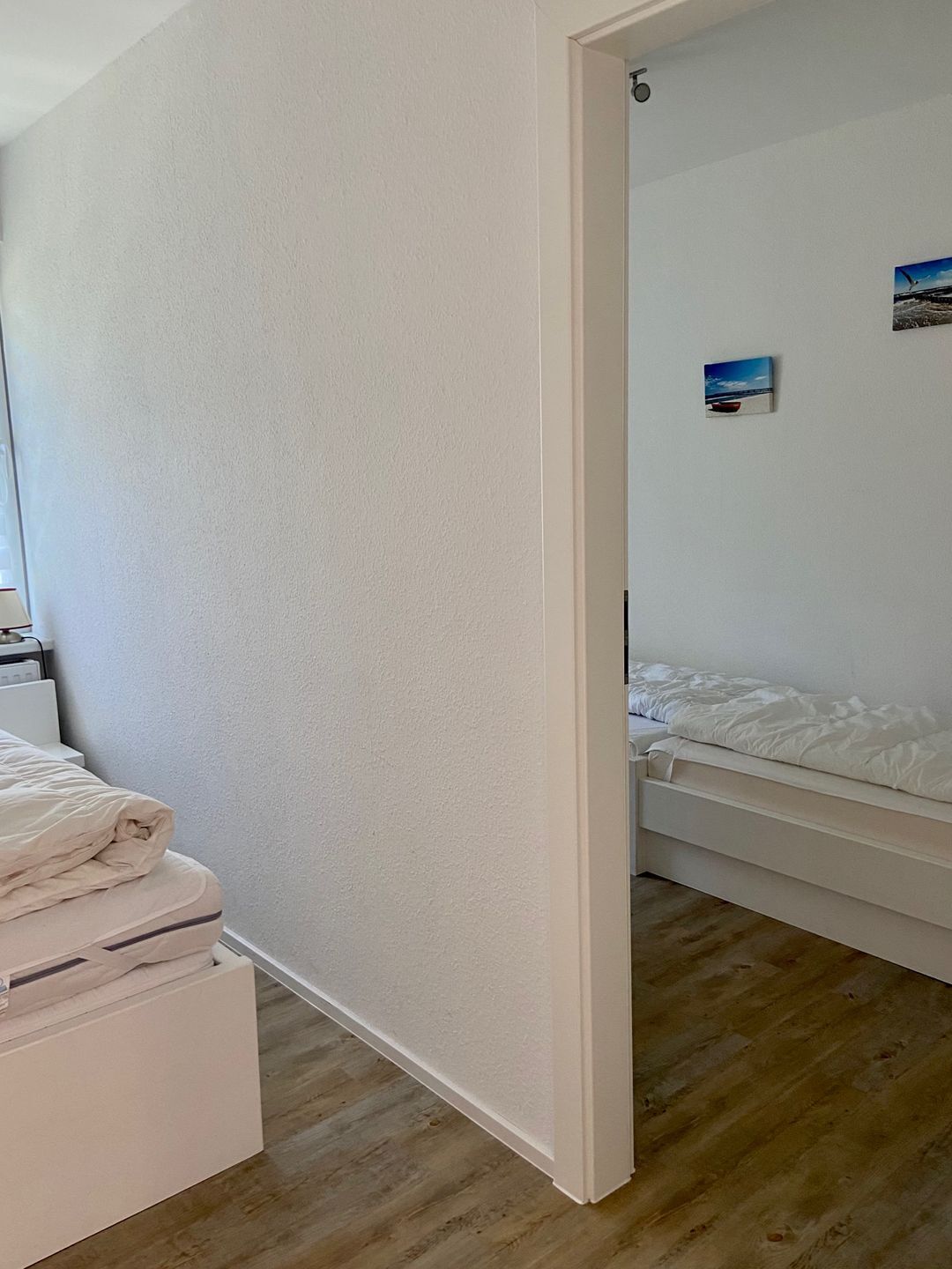 Ein Schlafzimmer mit einem Bett, einem kleinen Nachttisch und einem Wandbild.