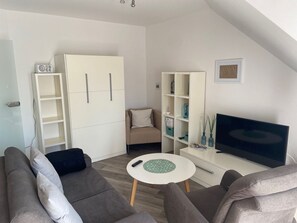 Ein modernes Wohnzimmer mit einer Couch, einem Fernseher, einem kleinen Tisch und integrierten Regalen.