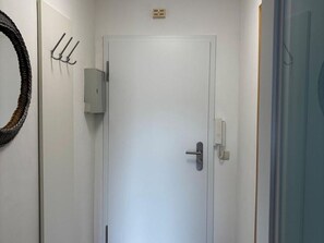 Eine weiße Tür mit Griff, ein an der Wand befestigter Lichtschalter und ein kleiner Stromverteiler.