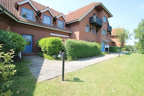 A two-story brick building with a red-tiled roof, a blue door, and a small balcony on the second floor. - 7008 - An der Aue 9a - 7008 - "Domicil" - An der Aue 9a - Apartment 19 (Dahme)